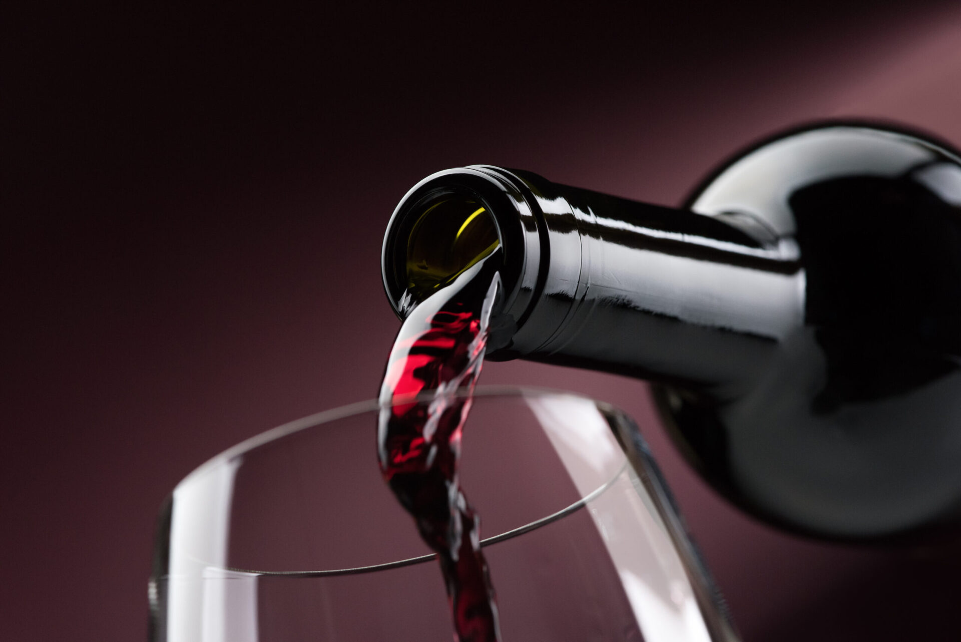 Pouring red wine from a bottle into a wineglass: wine tasting and celebration